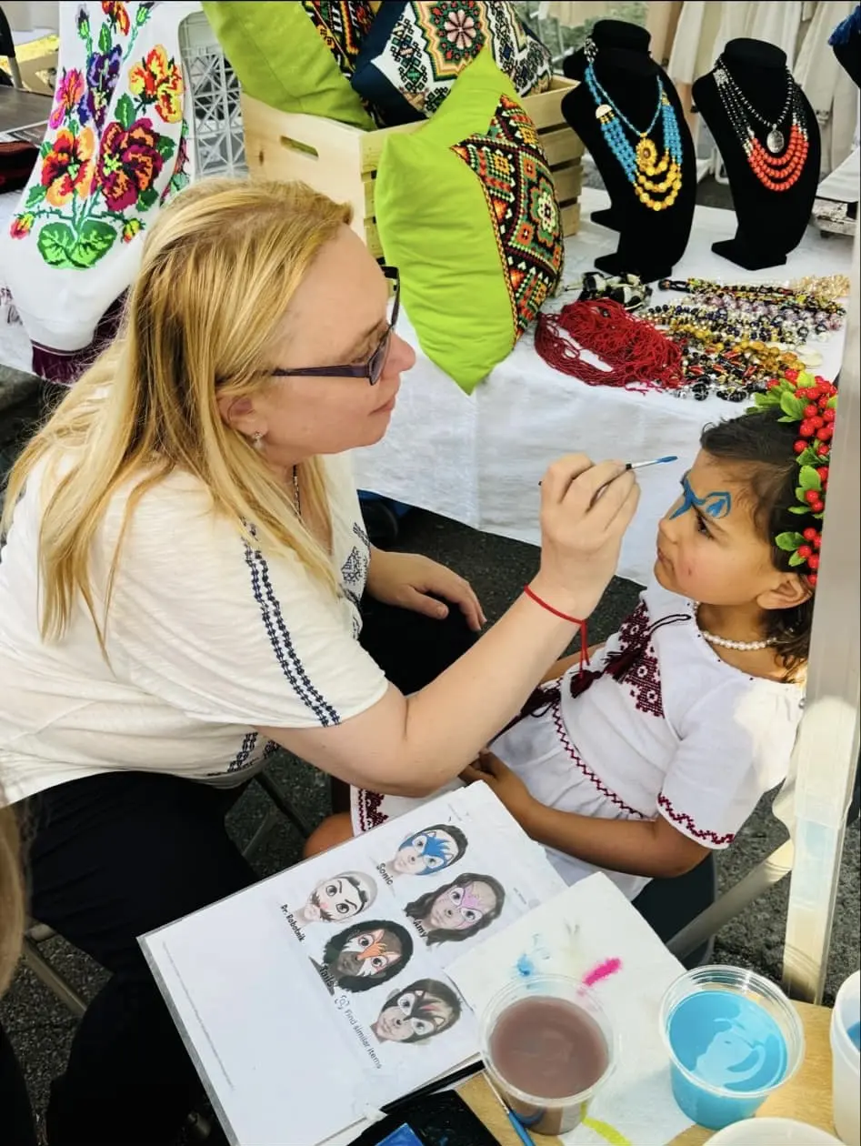 Painting faces A woman is painting the face of a child.
