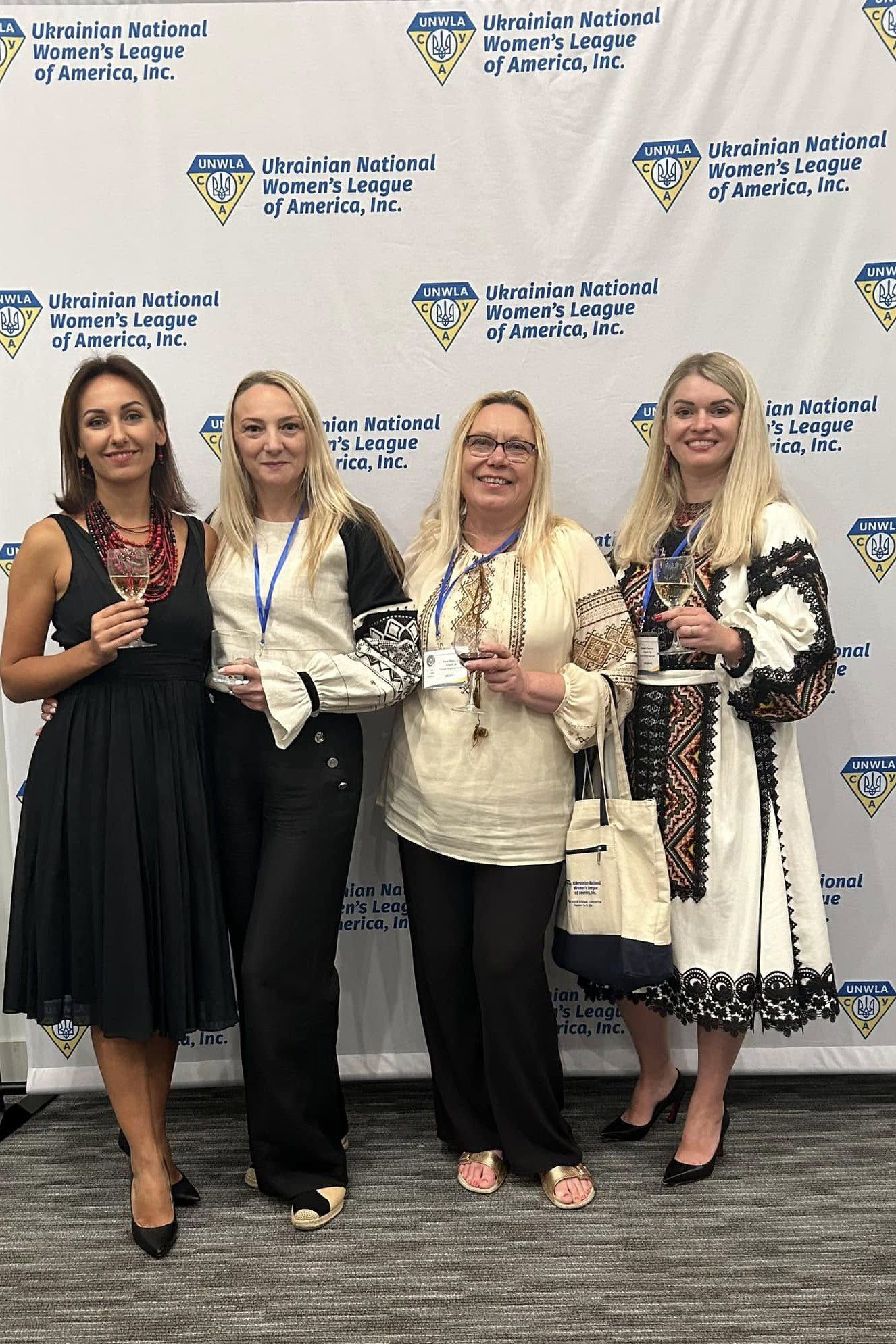 Ukrainianbranch#36- Four women holding wine glasses in front of a white wall.
